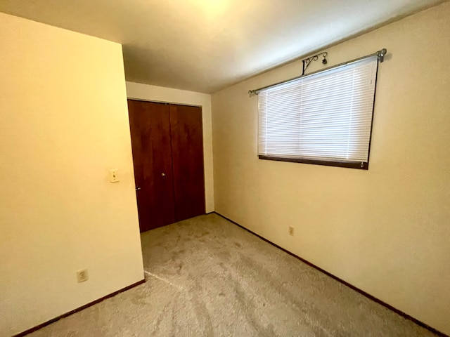 unfurnished bedroom with light carpet and a closet