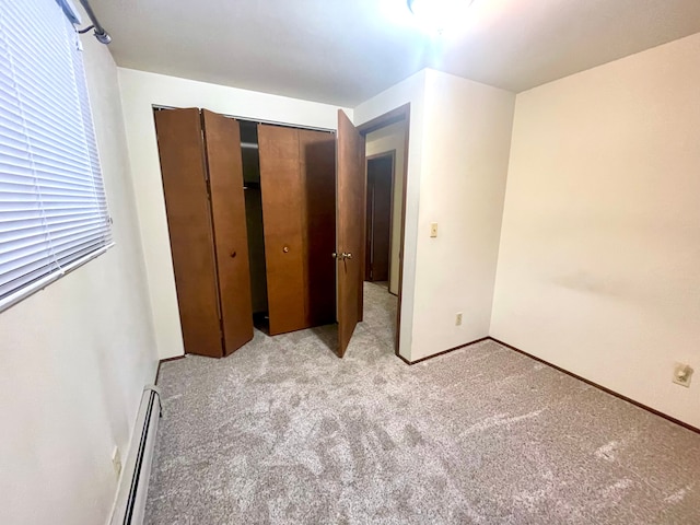 unfurnished bedroom with light carpet, a baseboard radiator, and a closet