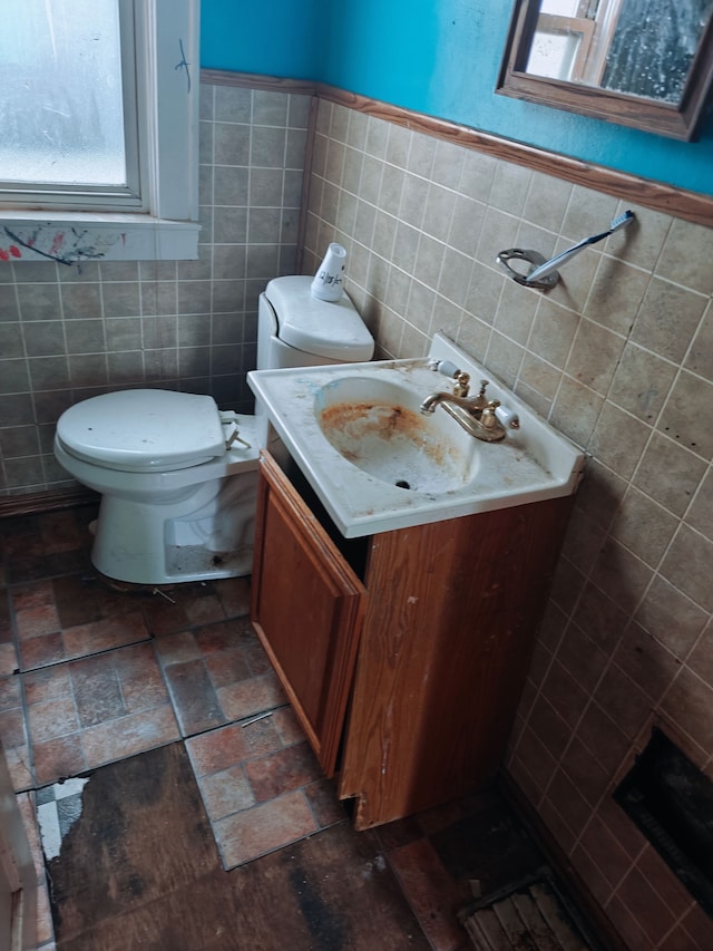 bathroom with vanity, toilet, and tile walls