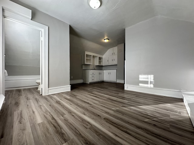 unfurnished living room featuring dark hardwood / wood-style floors, lofted ceiling, and sink