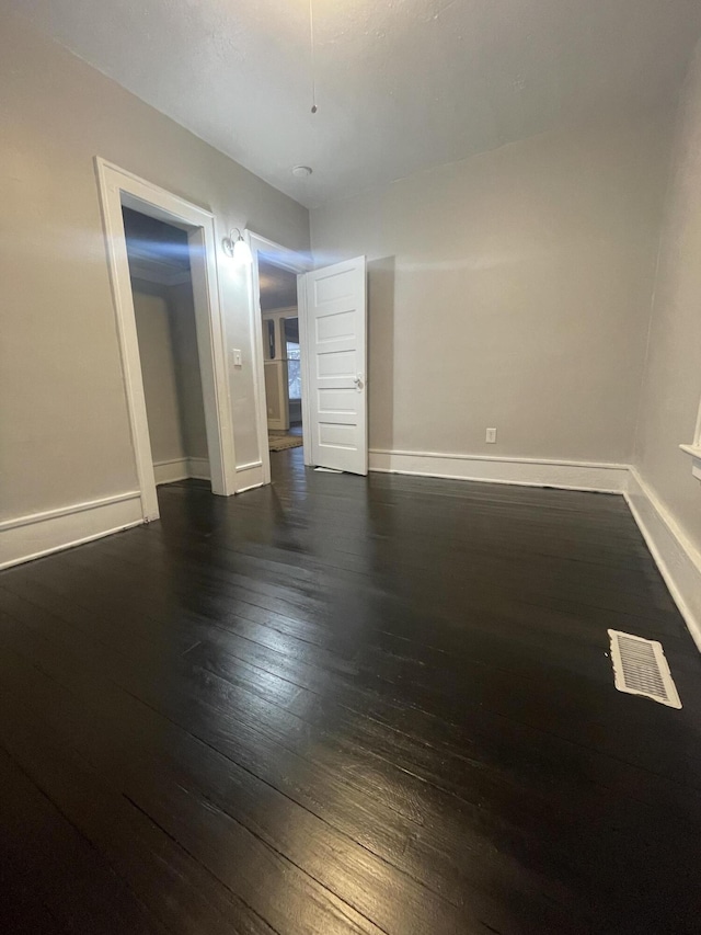 unfurnished room with dark wood-type flooring