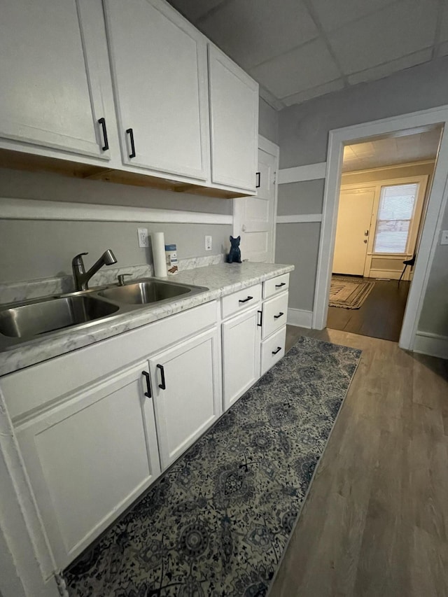 kitchen with white cabinetry, a drop ceiling, dark wood-type flooring, and sink