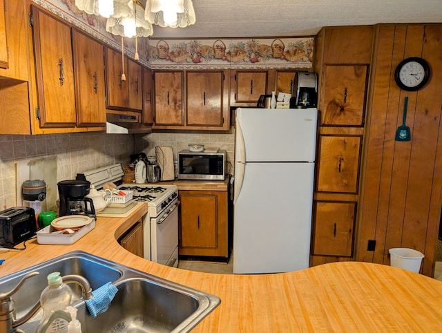 kitchen with gas stove, sink, tasteful backsplash, and white refrigerator