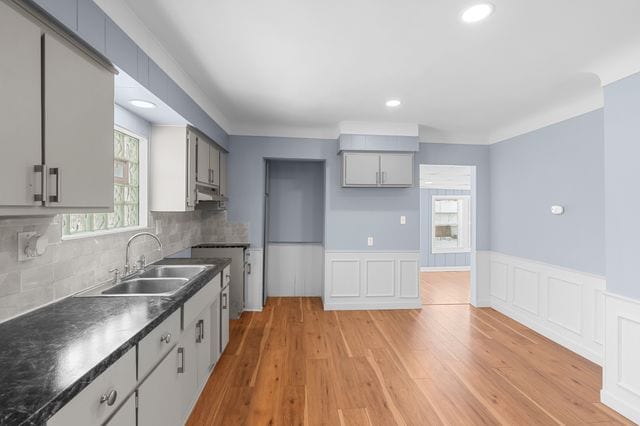 kitchen with gray cabinetry, decorative backsplash, sink, and light hardwood / wood-style floors