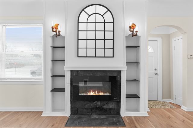 living room featuring built in shelves, a fireplace, and light wood-type flooring