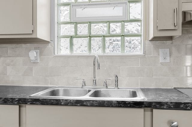 kitchen featuring decorative backsplash, white cabinets, a healthy amount of sunlight, and sink