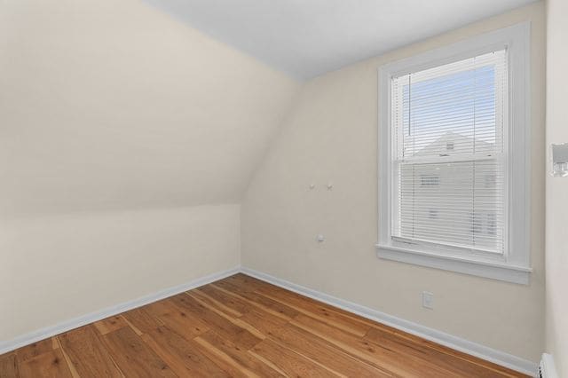 bonus room with baseboard heating, vaulted ceiling, and light wood-type flooring