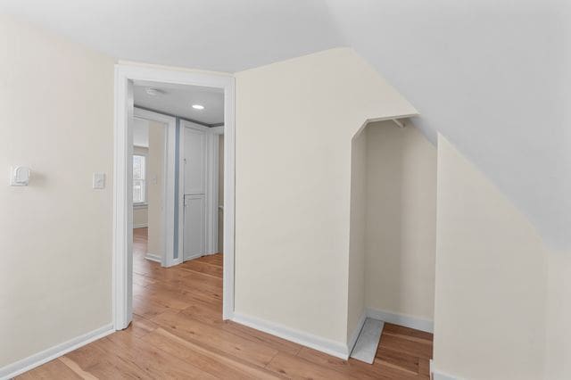 hall featuring light hardwood / wood-style flooring and lofted ceiling