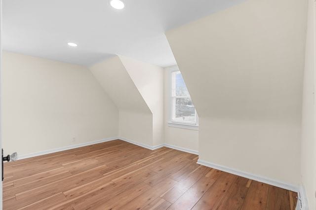 bonus room with lofted ceiling and light wood-type flooring