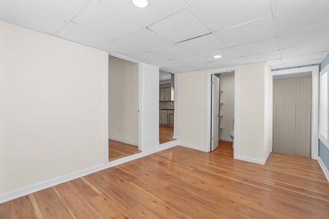 unfurnished bedroom with ensuite bath and wood-type flooring