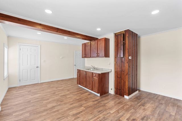 kitchen with crown molding, sink, and light wood-type flooring