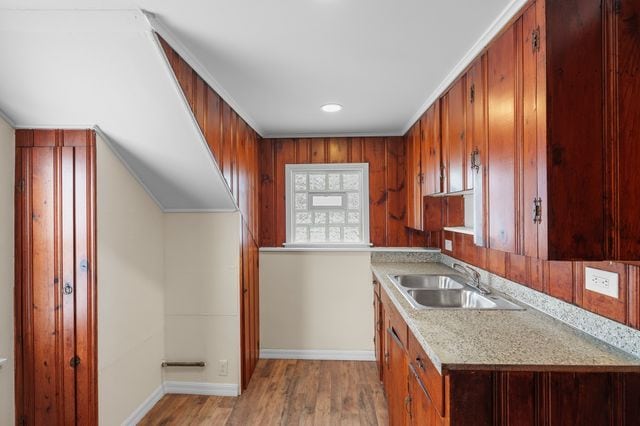 kitchen with sink, ornamental molding, and light hardwood / wood-style flooring