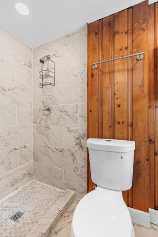 bathroom featuring tiled shower and toilet