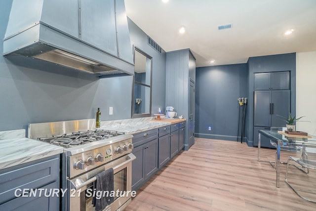 kitchen featuring light wood-type flooring, stainless steel stove, and light stone counters