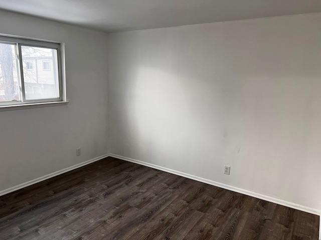 unfurnished room with baseboards and dark wood-style floors