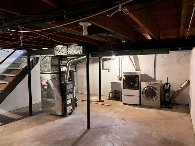 unfinished basement with a sink, heating unit, and washing machine and dryer