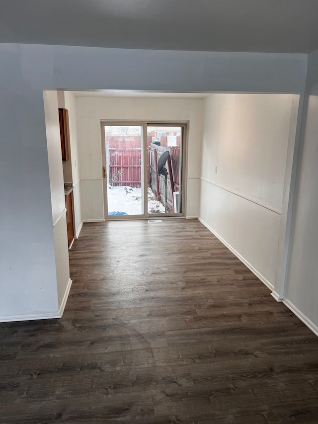 spare room with dark wood-style floors and baseboards