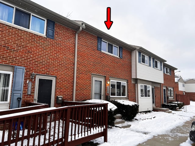 snow covered house featuring brick siding