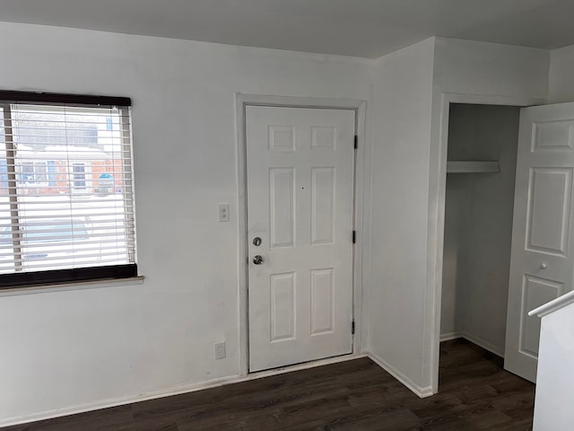 foyer entrance with dark wood-type flooring and baseboards