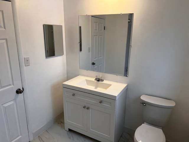 bathroom featuring marble finish floor, toilet, vanity, and baseboards