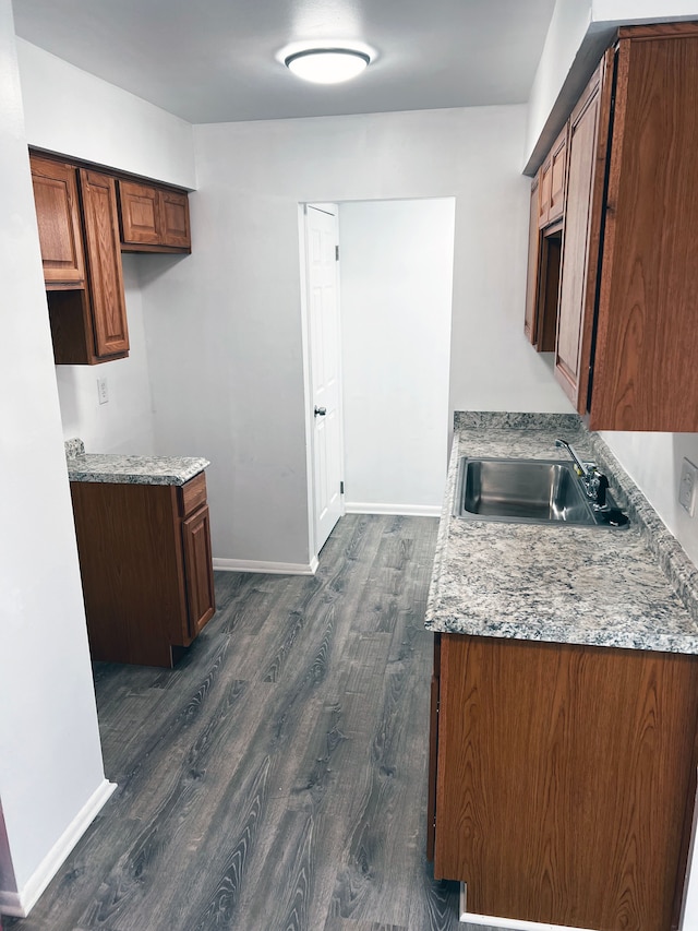 kitchen featuring a sink, baseboards, and dark wood-style flooring