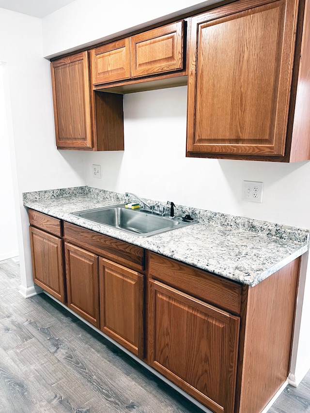 kitchen featuring light wood finished floors, brown cabinets, light countertops, and a sink