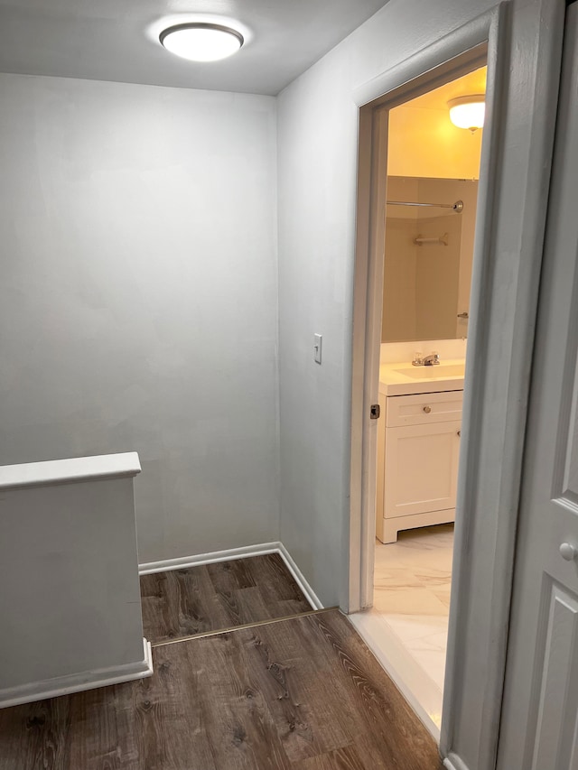 corridor with dark wood-type flooring, baseboards, and a sink