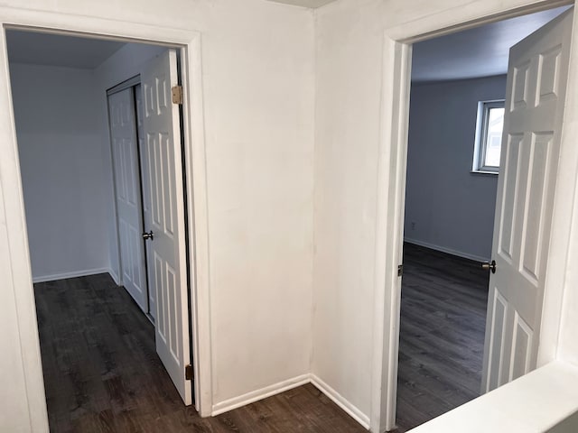 corridor with dark wood-style floors and baseboards