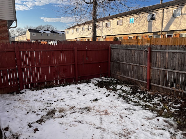 yard covered in snow with a residential view and fence