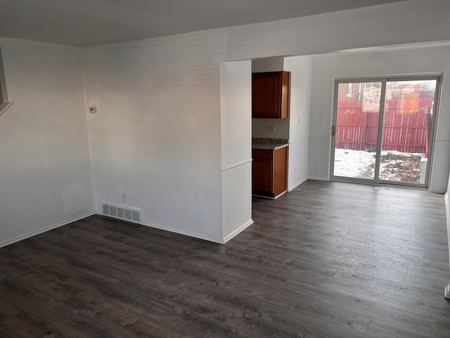 empty room with visible vents, baseboards, and dark wood finished floors