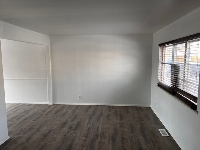 spare room with baseboards, visible vents, and dark wood-style flooring