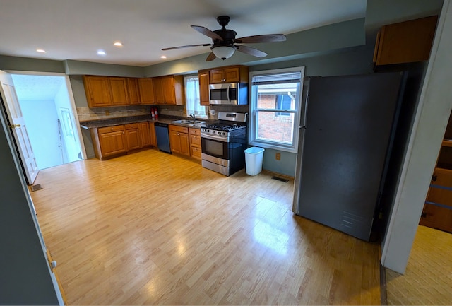 kitchen with decorative backsplash, sink, appliances with stainless steel finishes, and light hardwood / wood-style flooring