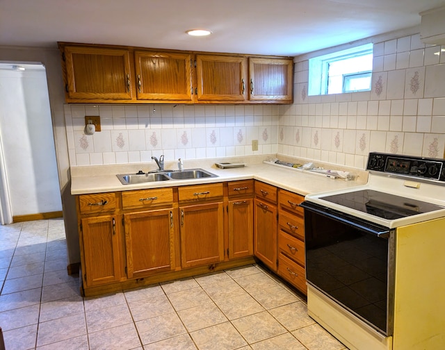 kitchen with white electric range, sink, light tile patterned floors, and tasteful backsplash