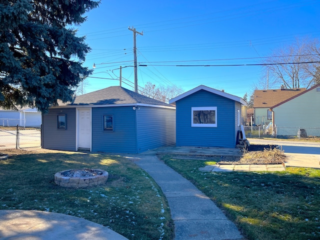 exterior space with an outbuilding, a front yard, and an outdoor fire pit