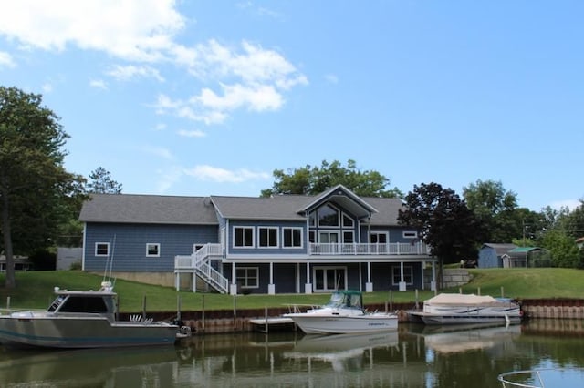 back of property with a yard and a water view