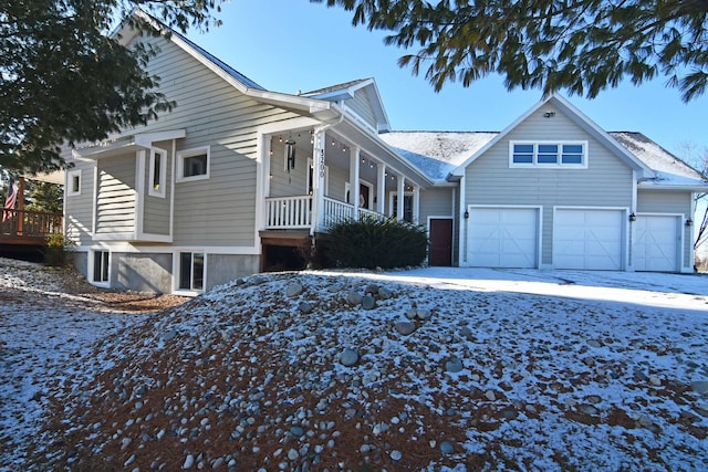 view of snowy exterior featuring covered porch and a garage