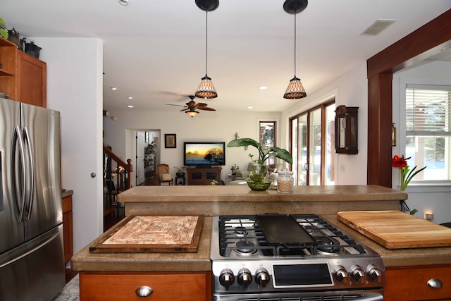 kitchen with ceiling fan, a center island, stove, and stainless steel refrigerator