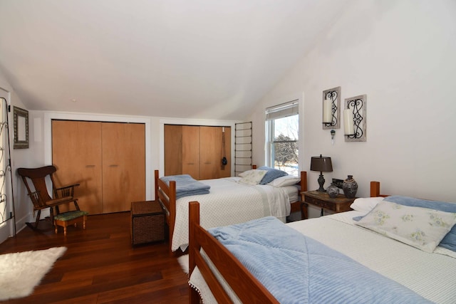 bedroom with vaulted ceiling, multiple closets, and dark hardwood / wood-style floors