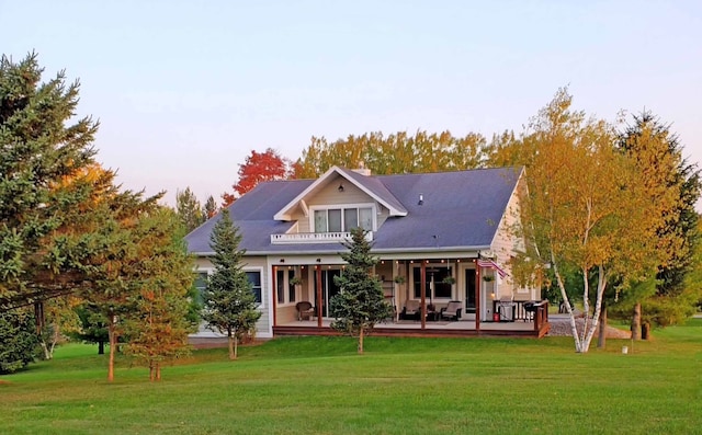 back house at dusk featuring a yard and a deck