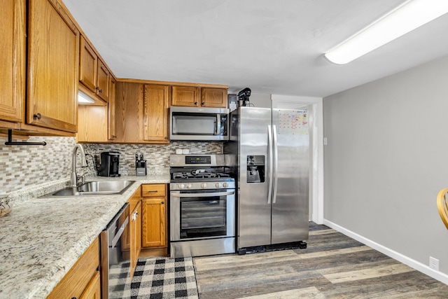 kitchen featuring sink, decorative backsplash, dark hardwood / wood-style floors, light stone countertops, and stainless steel appliances