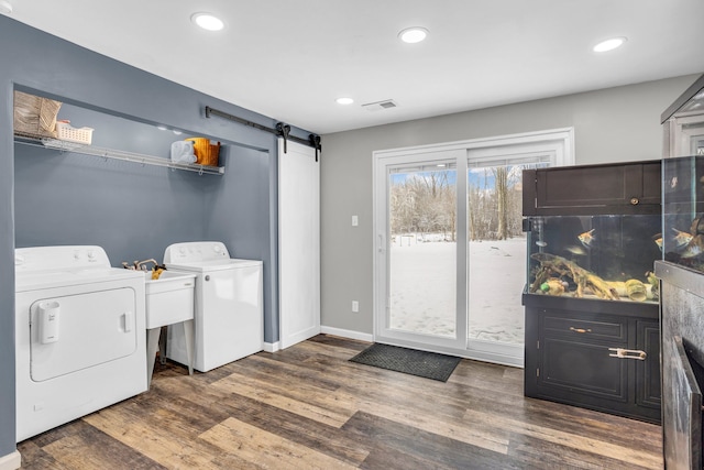 laundry room with a barn door, separate washer and dryer, and dark wood-type flooring