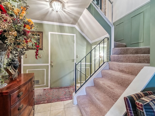 stairway featuring crown molding, lofted ceiling, and tile patterned floors