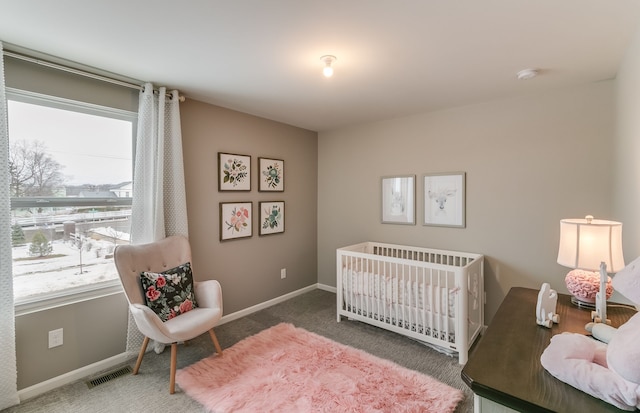 carpeted bedroom featuring multiple windows and a crib