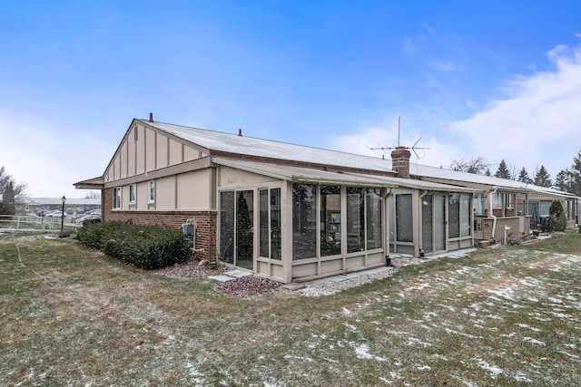 rear view of property with a lawn and a sunroom