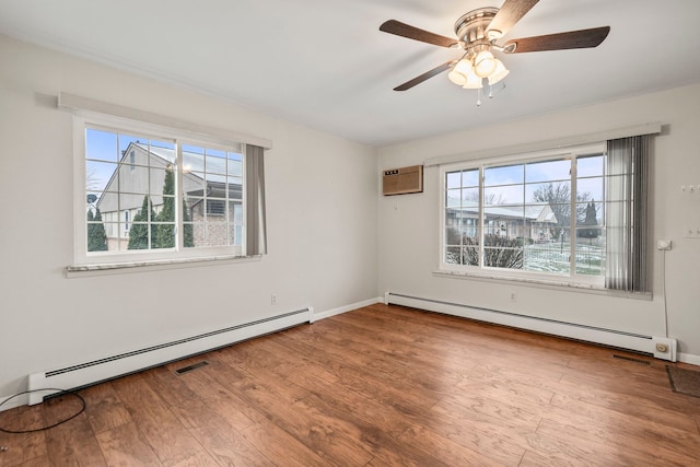 spare room with a baseboard heating unit, plenty of natural light, and hardwood / wood-style floors