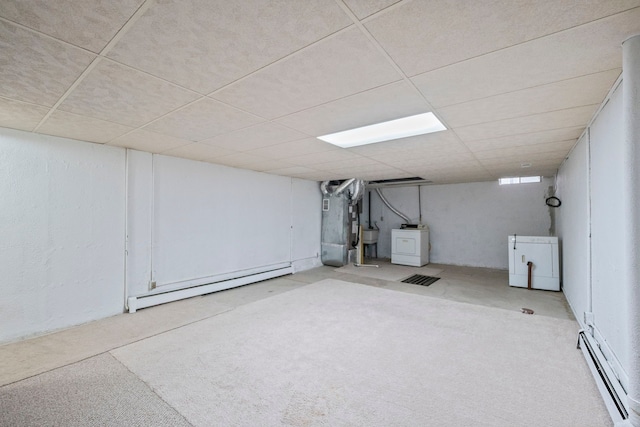 basement featuring heating unit, a baseboard heating unit, a paneled ceiling, and independent washer and dryer