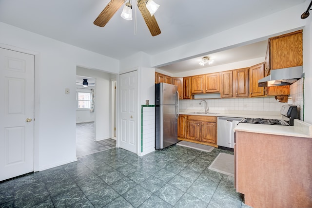 kitchen featuring appliances with stainless steel finishes, ceiling fan, sink, range hood, and tasteful backsplash