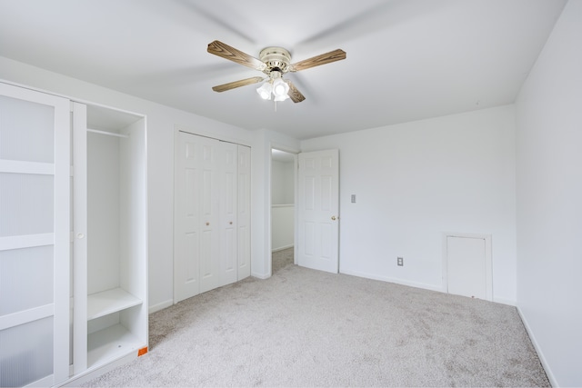 unfurnished bedroom with ceiling fan, light carpet, and multiple closets