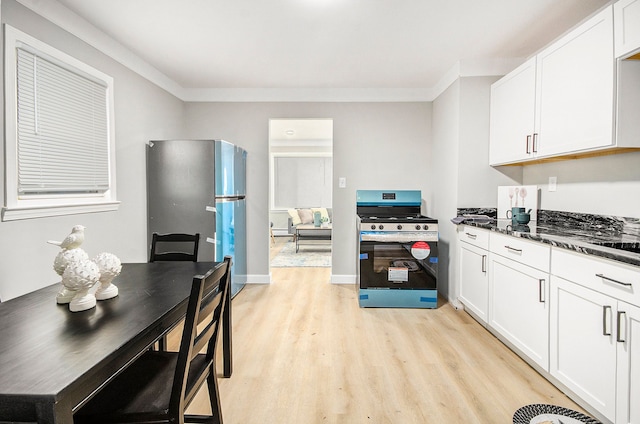 kitchen featuring appliances with stainless steel finishes, crown molding, dark stone counters, white cabinets, and light wood-type flooring