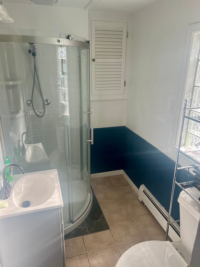 bathroom with tile patterned floors, vanity, a shower with door, and baseboard heating